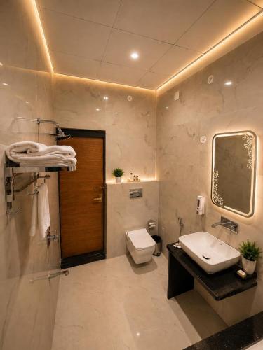 a bathroom with a toilet and a sink and a mirror at Hotel KS Palace in Varanasi