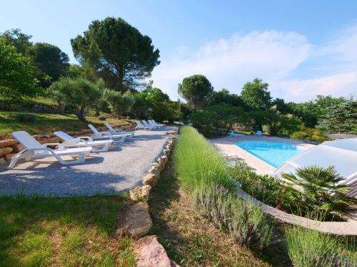 a row of white lounge chairs next to a swimming pool at Campagne SAINT MAURINET in Montmeyan