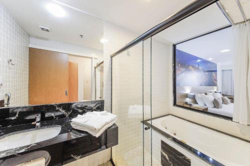 a bathroom with a tub and a sink and a window at Trade Hotel in Juiz de Fora