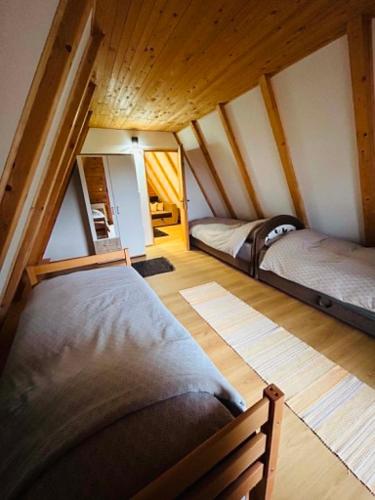 a bedroom with two beds in a room with wooden ceilings at Vikendica Hills Vlašić in Šišava