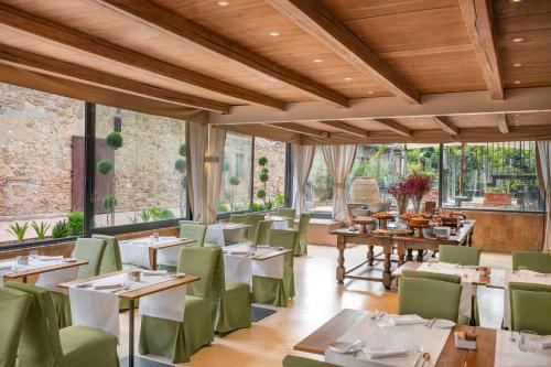a restaurant with white tables and green chairs at Borgo Tre Vaselle in Torgiano