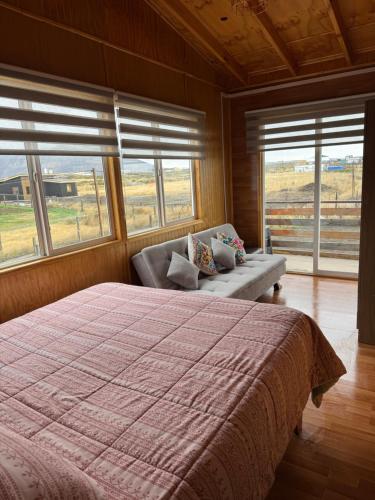 a bedroom with a bed and a couch and windows at Depto huerto 23 in Puerto Natales