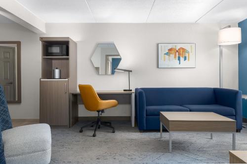 a living room with a blue couch and a desk at Holiday Inn Express & Suites Memphis East by IHG in Memphis