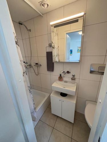 a bathroom with a sink and a tub and a mirror at Haus zur Eiche Private 1 Zimmerstudios in Chur