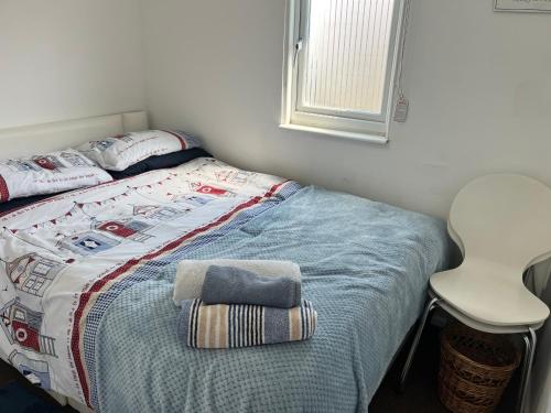 a bed with a blanket and a chair in a room at The Lookout in Leysdown-on-Sea