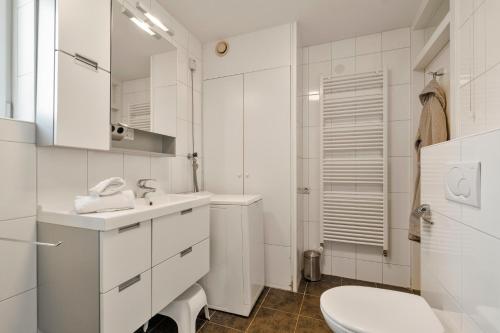 a white bathroom with a sink and a toilet at Dorpsplein 42 in Callantsoog