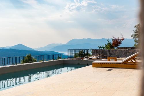 a swimming pool with a chair and a view of the mountains at Villa Verdura in Budva