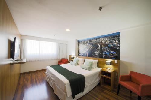 a hotel room with a bed and a painting on the wall at Trade Hotel in Juiz de Fora