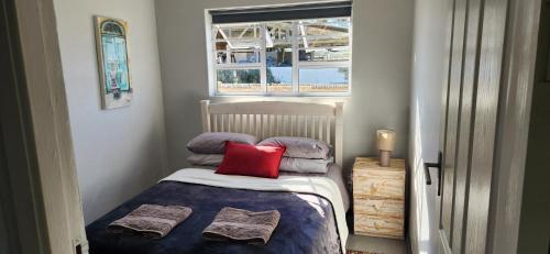 a small bedroom with a bed with a red pillow at Volgenoeg Self Catering Cottage in Oudtshoorn