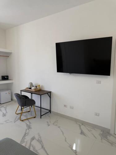 a room with a chair and a television on a wall at Alexandra Rooms & Suitess in Sassari