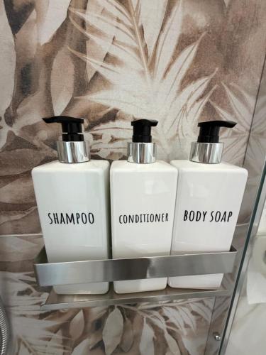 two bottles of shampoo and conditioner on a glass shelf at Alexandra Rooms & Suitess in Sassari