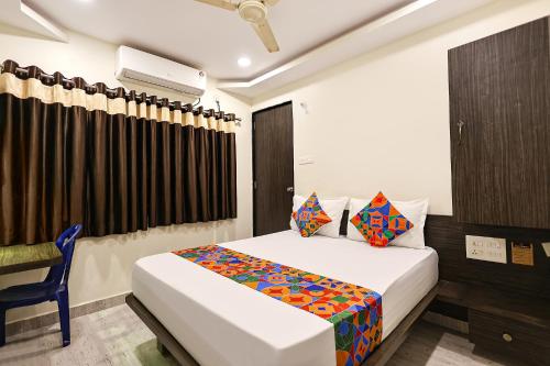 a hotel room with a bed and a chair at FabHotel Happy in Vijayawāda