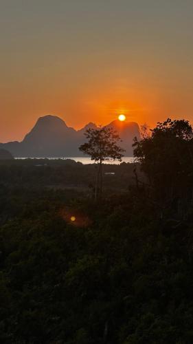 a sunset over a field with trees and mountains at Vista Cadlao in El Nido