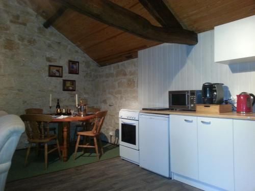 Il comprend une cuisine avec une petite table et des appareils électroménagers blancs. dans l'établissement Les Roses Trémières, à Lezay