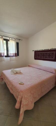 a bedroom with a large bed with a pink spread at Sorres Agriturismo in Tanaunella