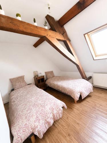 a attic bedroom with two beds and a window at La maison du soleil in Cappellebrouck