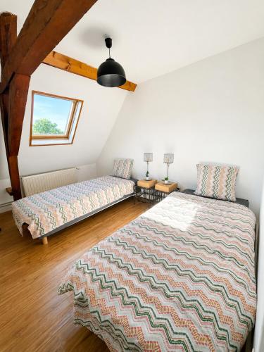 a bedroom with two beds and a window at La maison du soleil in Cappellebrouck