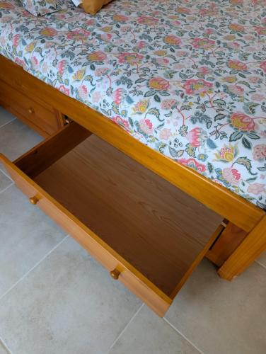 a bed with a wooden frame with a floral pattern on it at Studio cozy 2pp wifi in La Sicaudais