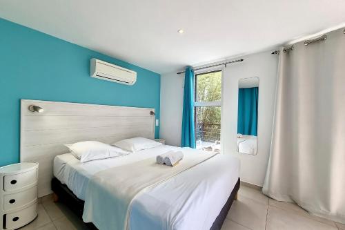 a bedroom with a large white bed with blue walls at Aybowan - Jacuzzi - Climatisation in Les Avirons