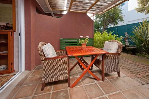 una mesa de madera y 2 sillas en el patio en Brown Jug Guest House, en Hermanus