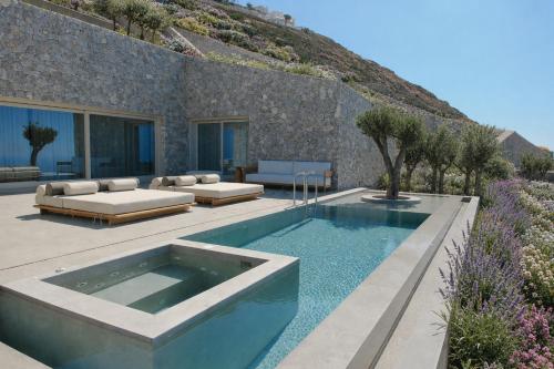 a swimming pool in the middle of a patio with a house at VOUNO Santorini Private Villas in Pyrgos