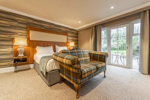 a bedroom with a bed and a chair and a window at Dunadry Hotel And Gardens in Antrim