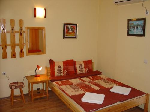 a bedroom with a bed and a table with a lamp at Guest House Alex in Chernomorets