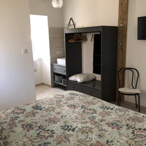 a bedroom with a bed and a dresser with a mirror at Les Lilas piscine partagée in Les Vans