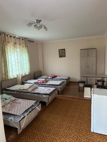 a room with four beds in it with a table at Достук in Bosteri