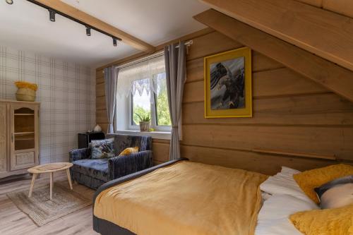 a bedroom with a bed and a chair and a window at Przytulisko Bieszczady in Smerek