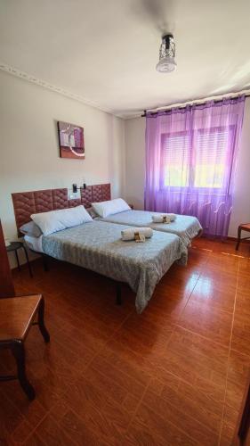 a bedroom with two beds and a wooden floor at Pensión Casa Vicente in Tineo