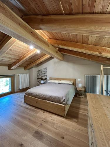 a bedroom with a bed and wooden ceilings at La Mizoun dë Miquél in Ostana
