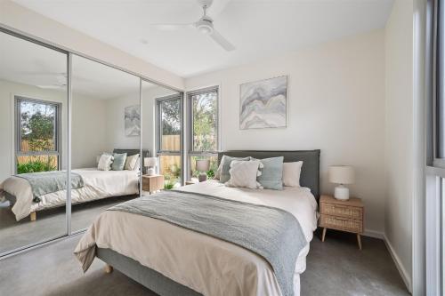 a bedroom with a large bed and two windows at The Cape Collective 5 in Margaret River Town