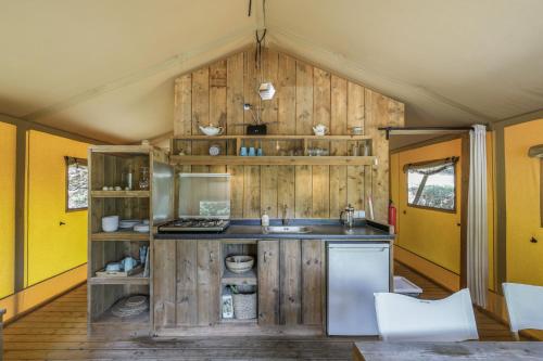 a kitchen with wooden cabinets and a sink in a room at Glamping - Quinta do Cascalhal in Arco de Baúlhe