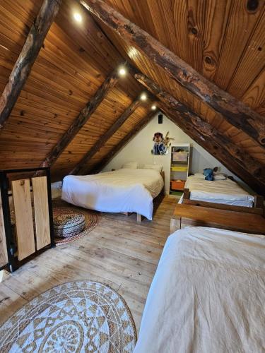 a attic bedroom with two beds and wooden ceilings at La Parenthèse Enchantée Chalet in Beuil
