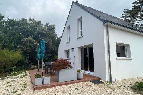 a white house with potted plants on a wooden deck at Maison Tamaris avec jardin et clos in Quiberon