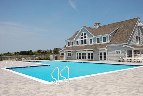 a house with a swimming pool in front of a house at 2433 - Bella Bay in Duck