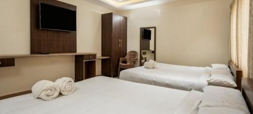 a hotel room with two beds and a flat screen tv at Jazz Inn in Tiruvallūr