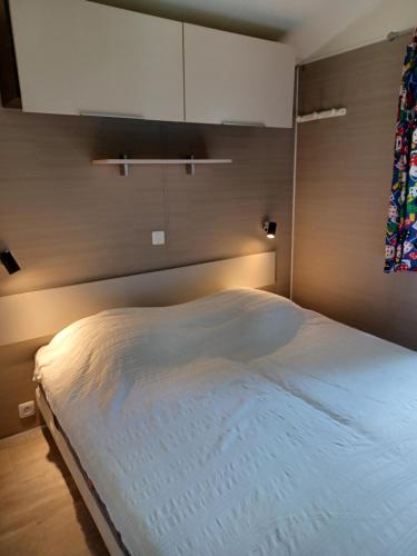 a bedroom with a large bed with a white blanket at Mobil home Vegas in Blangy-le-Château