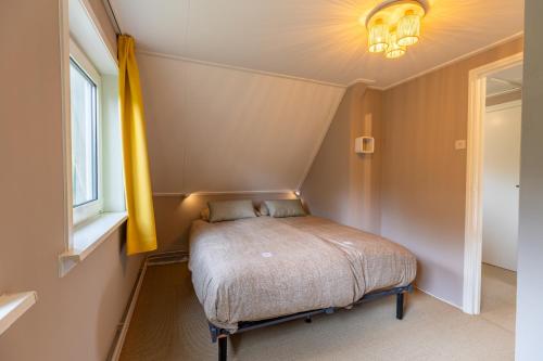 a small bedroom with a bed with a yellow curtain at Stille Wille in Ballum