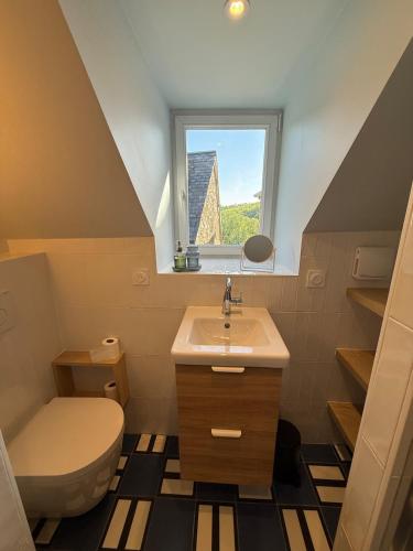 a bathroom with a sink and a toilet and a window at Le Cosy in Coutances