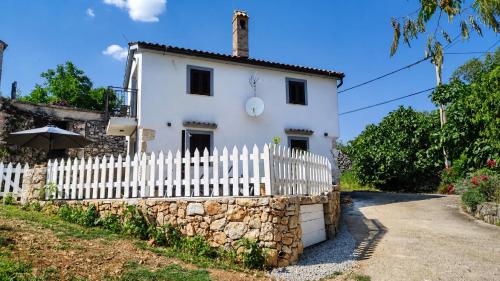 a white house with a white picket fence at Holiday home Brseč in Mošćenička Draga