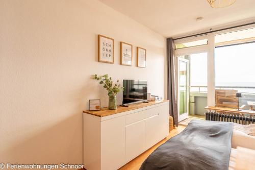 a living room with a tv on a white dresser at Waterkant in Schilksee