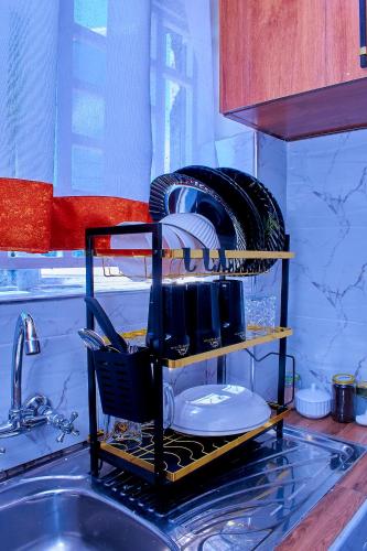 a kitchen sink with a dish drying rack with dishes at Branson Comfort Inn in Kakamega