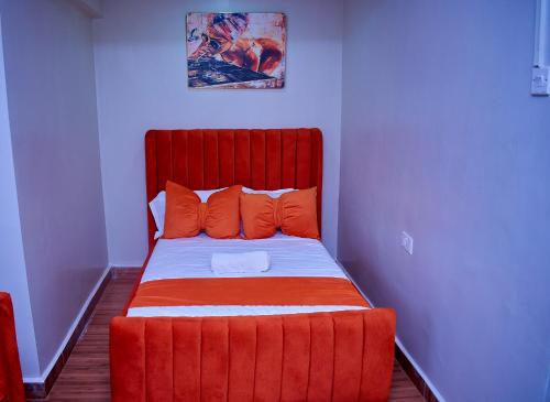 a red bed with orange pillows in a room at Branson Comfort Inn in Kakamega