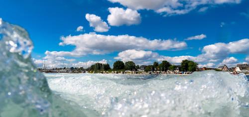 ein Wasserkörper mit einem Strand im Hintergrund in der Unterkunft ACQUA Strande Yachthotel & Restaurant in Strande