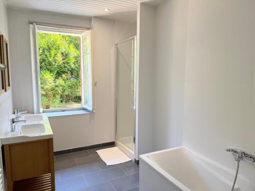 a bathroom with a tub and a sink and a window at La maison du lac in Vions