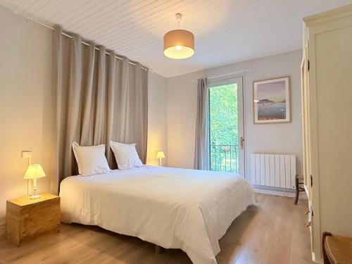 a bedroom with a white bed and a large window at La maison du lac in Vions