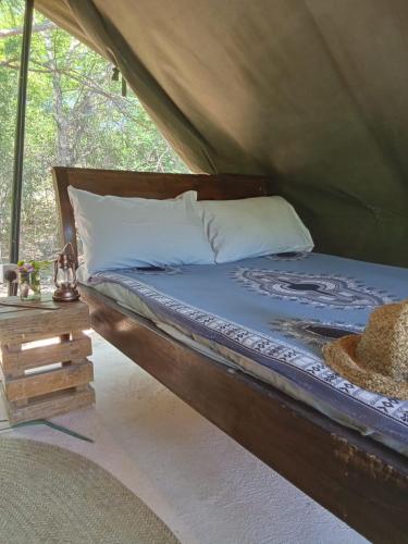 a bed in a tent with a blue comforter and pillows at The Shamba in Kilifi