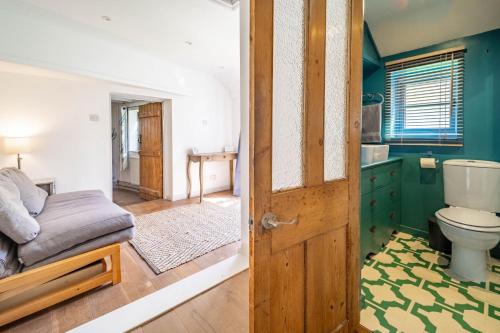 a bathroom with a bed and a toilet in a room at Ruthie Cottage in Bacton